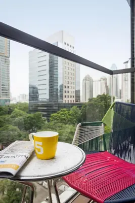 a yellow coffee cup sitting on a table on a balcony at Hotel Indigo Bangkok Wireless Road by IHG in Bangkok