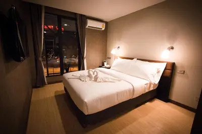 a bedroom with a bed with white sheets and a window at C U Inn Bangkok in Bangkok