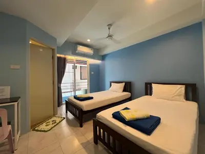 a bedroom with two beds and a blue wall at Bonita House in Bangkok