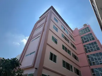 a pink building with a blue sky in the background at Bonita House in Bangkok