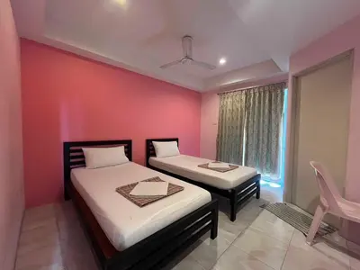 two beds in a room with a pink wall at Bonita House in Bangkok