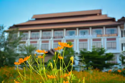 a building in the background with orange flowers in the foreground at The Choice Hotel - Adults Only in Bangkok