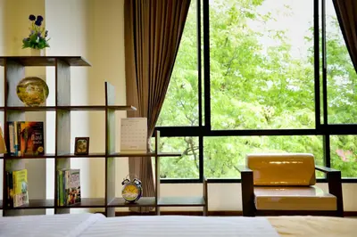 a bedroom with a bed and a chair and a window at The Choice Hotel - Adults Only in Bangkok