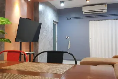 a dining room with a table and a tv on a wall at The Lake Guest House in Ban Bang Phang