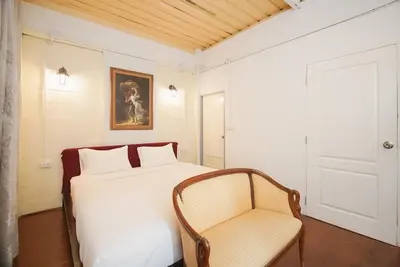 a bedroom with a white bed and a chair at XX Mitr Inn Yaowarat - มิตร อินน์ เยาวราช in Khlong San