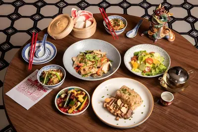 a wooden table with plates of food on it at XX Mitr Inn Yaowarat - มิตร อินน์ เยาวราช in Khlong San