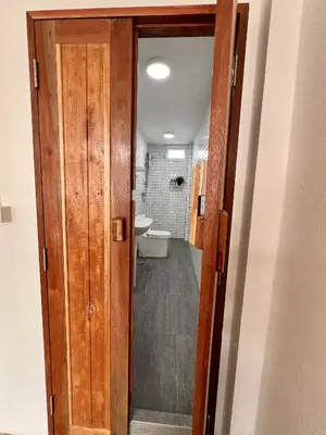 a door to a bathroom with a toilet and a sink at Sabay Home in Bangkok