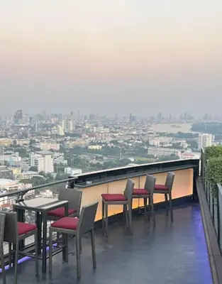 a group of chairs and tables on a balcony at Sathorn prime Panorama City View rooftop bar in Bangkok