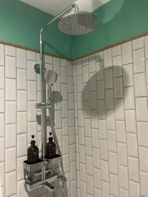 a shower in a bathroom with white tiles at The Palette Bangkok Hotel - Self check-in after 10 pm in Bangkok