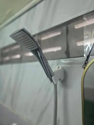 a shower head in a bathroom next to a mirror at 211 Spacious studio with breezy fan full amenities with free Wi-Fi in Bangkok