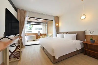 a bedroom with a large white bed and a television at Ratchathewi Hyde Away in Pratunam