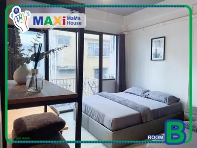 a bedroom with a bed and a table and a balcony at MAXi MaMa House in Bangkok