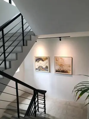a staircase with two paintings on the wall and a stair case at BaanTip​ HomStay in Bangkok
