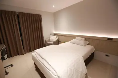 a bedroom with a white bed and a chair at BaanTip​ HomStay in Bangkok