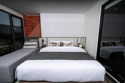 a bedroom with a large white bed with two chairs at WE HOTEL RIVERFRONT in Bang Su
