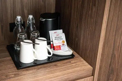 a shelf with cups and a book in a hotel room at WE HOTEL RIVERFRONT in Bang Su