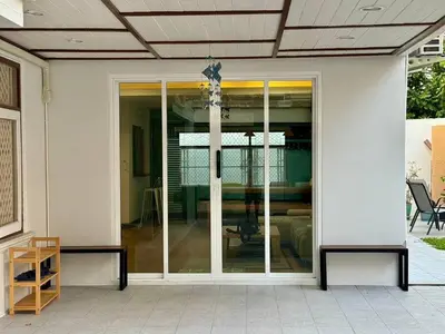 a sliding glass door of a house with a table at Stay Tender in Bang Su
