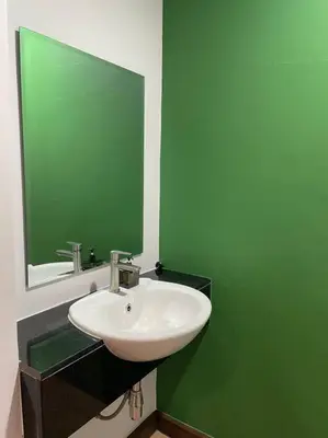 a bathroom with a sink and a green wall at Stay Tender in Bang Su