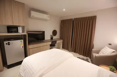 a hotel room with a bed and a tv at BaanTip​ HomeStay in Amphoe Phra Khanong