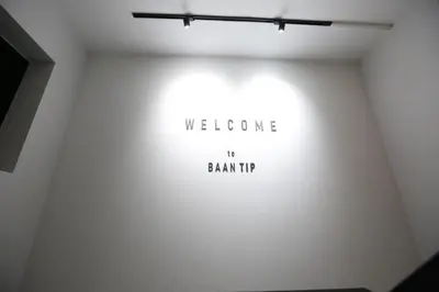 a white wall with a welcome sign on it at BaanTip​ HomeStay in Amphoe Phra Khanong