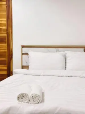 two towels are sitting on a white bed at Chubby 5 Room 4 in Ban Bang Bamru
