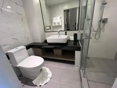 a bathroom with a toilet and a sink and a shower at ARNI Skye Hotel in Bangkok