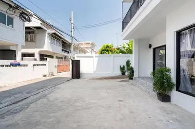 an empty driveway of a white house with a fence at MIQ Ekkamai3_Pool Villa_3BR house in Bangkok