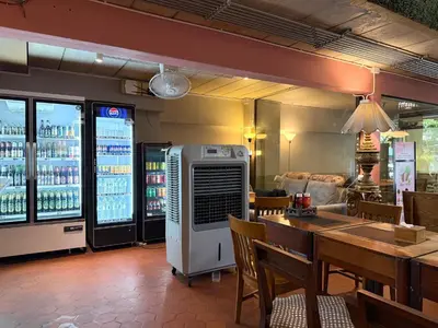 a restaurant with a bar with a table and a refrigerator at My House Guesthouse & Restaurant in Bangkok