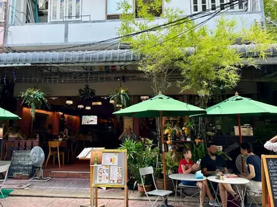 a group of people sitting at tables under green umbrellas at My House Guesthouse & Restaurant in Bangkok