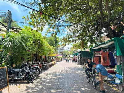 a man riding a bike down a street at My House Guesthouse & Restaurant in Bangkok