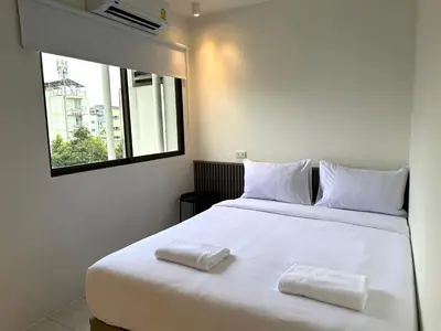 a bedroom with a white bed with two towels on it at My House Guesthouse & Restaurant in Bangkok