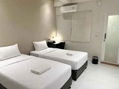 two beds in a hotel room with white sheets at My House Guesthouse & Restaurant in Bangkok