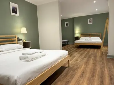 two beds in a bedroom with green walls and wooden floors at O'Shea's Sukhumvit Bangkok in Khlong Toei