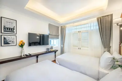 a hotel room with two beds and a tv at Cherie Bangkok Boutique Hotel in Bangkok