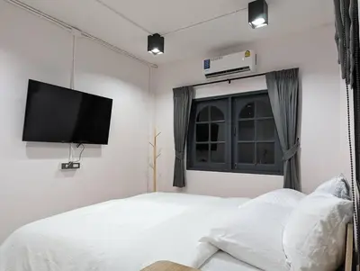 a bedroom with a white bed and a flat screen tv at Cloud9 Hometel - Entire House 3BR 170m to BTS Private Quiet & Comfy in Bangkok