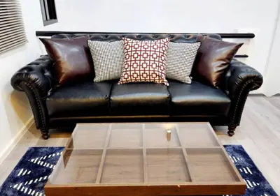 a black leather couch with pillows and a coffee table at Lasalle House - 4- storey entire house with rooftop 200 sqm Suvarnabhumi airport ,BTS in Bangkok