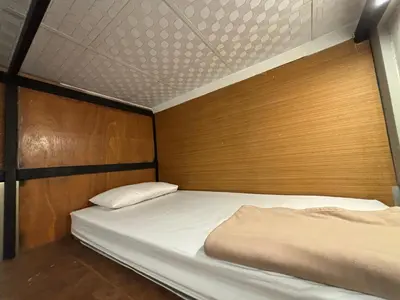 a bedroom with two beds and a wooden wall at Hansa Hostel Bangkok Khaosan in Bangkok