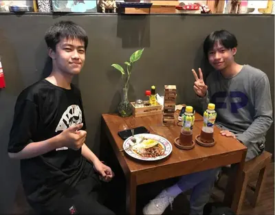 two young men sitting at a table with a plate of food at Hansa Hostel Bangkok Khaosan in Bangkok