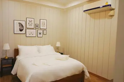 a bedroom with a large bed with white sheets at Wiengket Heritage 1964 in Bangkok