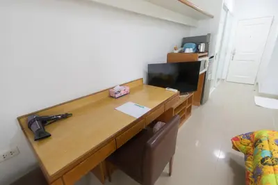 a wooden desk in a room with a television at Condo I-House Laguna Garden RCA - Behind Sukhumvit Thonglor Asoke Emporium Bangkok Hospital Piyavet Hospital Makkasan Airport Link MRT SKY TRAIN in Bangkok