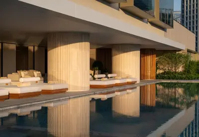 a hotel with a swimming pool with white lounge chairs at Dusit Thani Bangkok in Bangkok