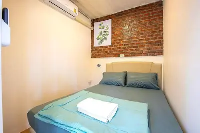 a bed in a small room with a brick wall at My Cocoon Hostel แจ้งวัฒนะ in Nonthaburi