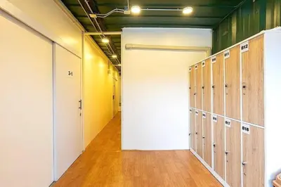 an empty locker room with a white door and wooden floors at My Cocoon Hostel แจ้งวัฒนะ in Nonthaburi