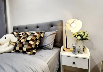 a bed with a side table with a lamp and flowers at Cozy House,4 rooms, bts ,Mega Bangna,Suvarnabhumi in Bangkok