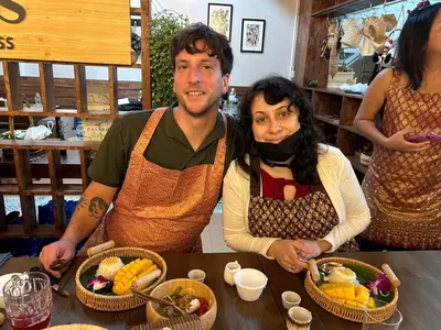 a man and a woman sitting at a table with food at Homies Ratchada Hotel in Bangkok