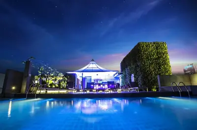 a large swimming pool with a building in the background at night at Amara Bangkok Hotel in Bangkok