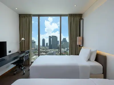 a hotel room with two beds and a desk at Amara Bangkok Hotel in Bangkok