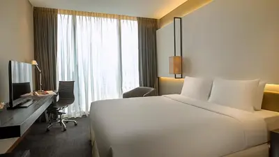 a hotel room with a large white bed and a desk at Amara Bangkok Hotel in Bangkok