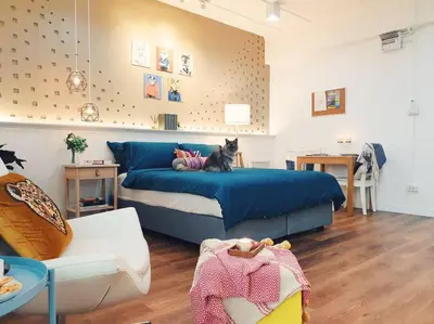 a cat sitting on a blue bed in a room at Double Studio, Private Bath & Balcony, Shared Kitchen with Local Family by Pillows & Purrs in Bangkok