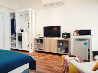 a living room with a tv on a entertainment center at Double Studio, Private Bath & Balcony, Shared Kitchen with Local Family by Pillows & Purrs in Bangkok